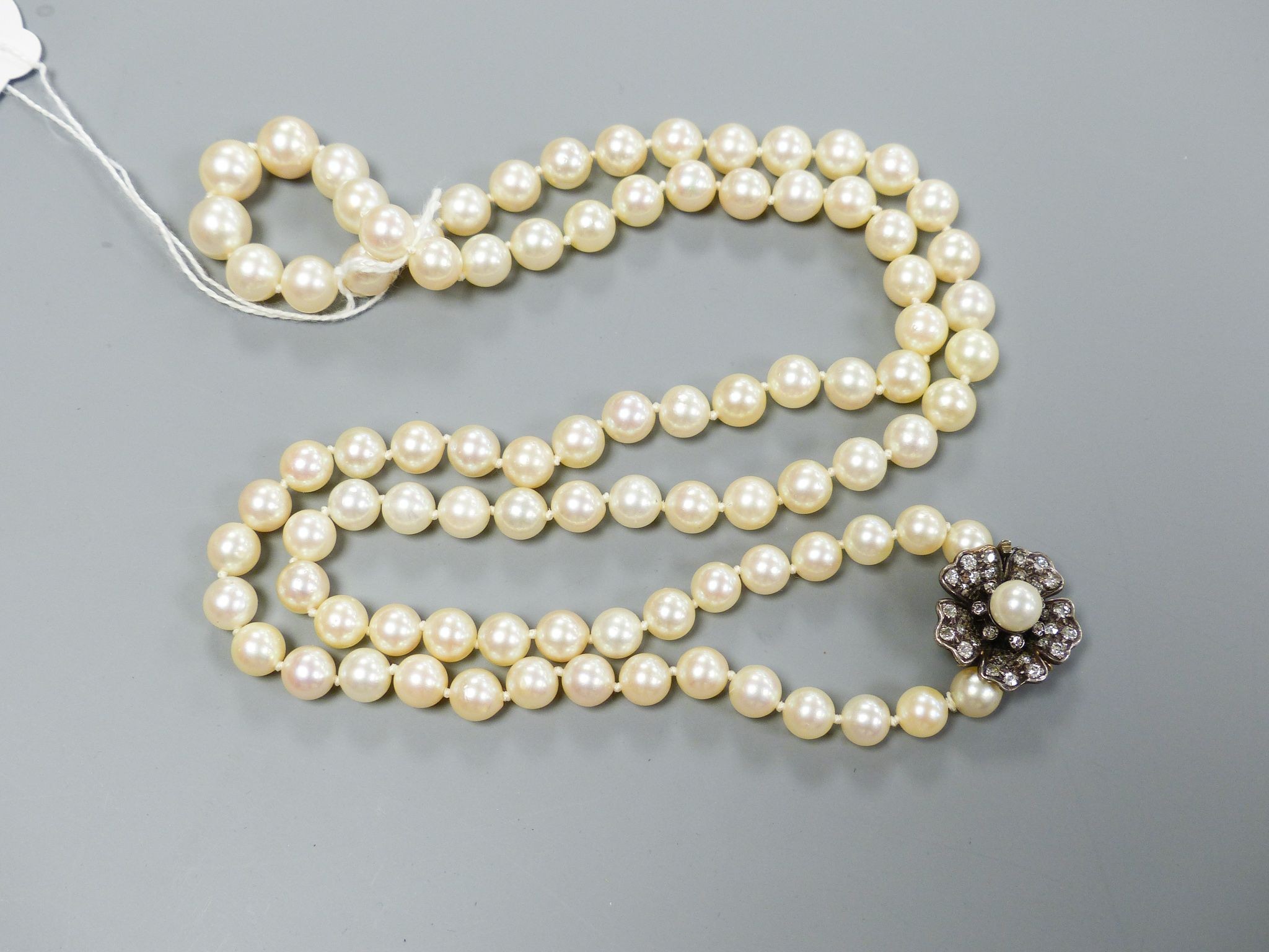 A single strand graduated cultured pearl necklace, with yellow metal, diamond and cultured pearl set flower head cluster clasp, 76cm, largest pearl diameter 94mm, gross weight 66 grams.